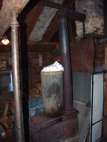Large wood stove with the radiator tank filled with snow.