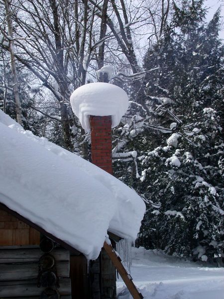 The snow on the roof and piled on the fireplace chimney.