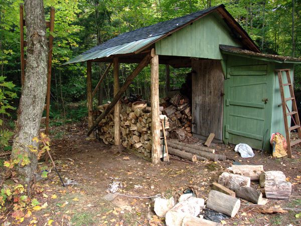 Finished wood shed with newly cut wood stacked.