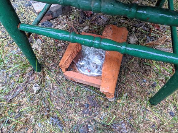 Melted aluminum "cast" and cooling, sheltered from the rain under a chair.