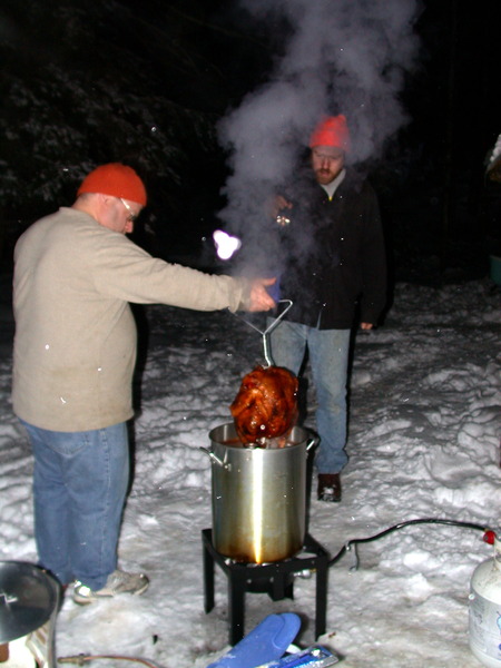 Jon removing the cooked turkey from the deep fryer with bill providing light.